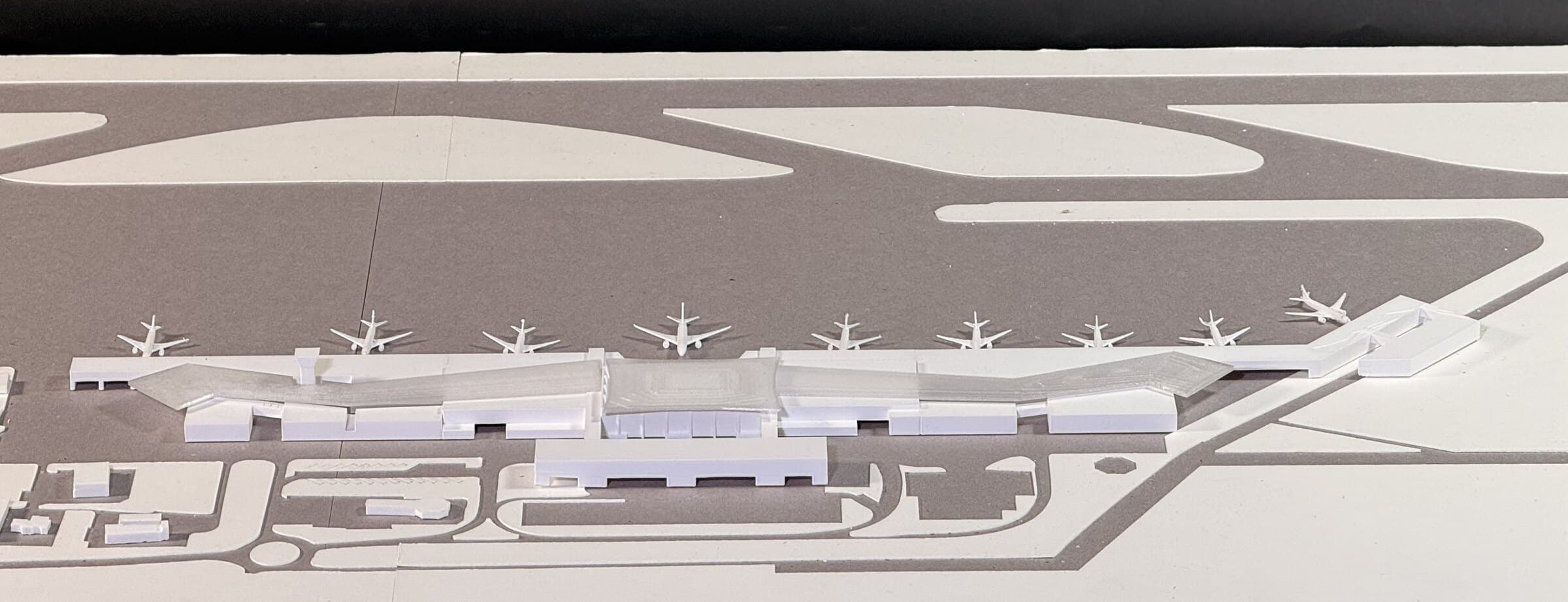 Aerial photograph of the airport site model, the terminal building's footprint beside a runway marked with aircraft silhouettes.