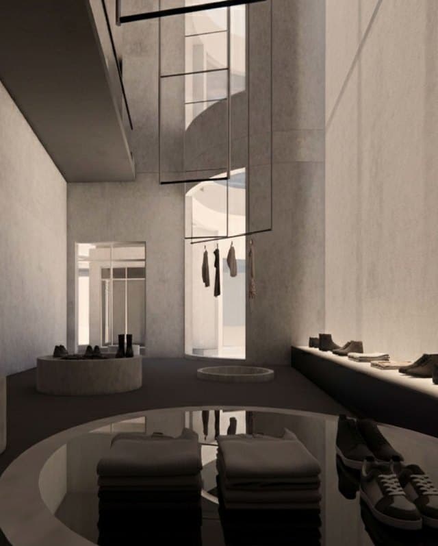 Rendering of a tall display space with hanging garments and a low circular platform of folded clothing and shoes.