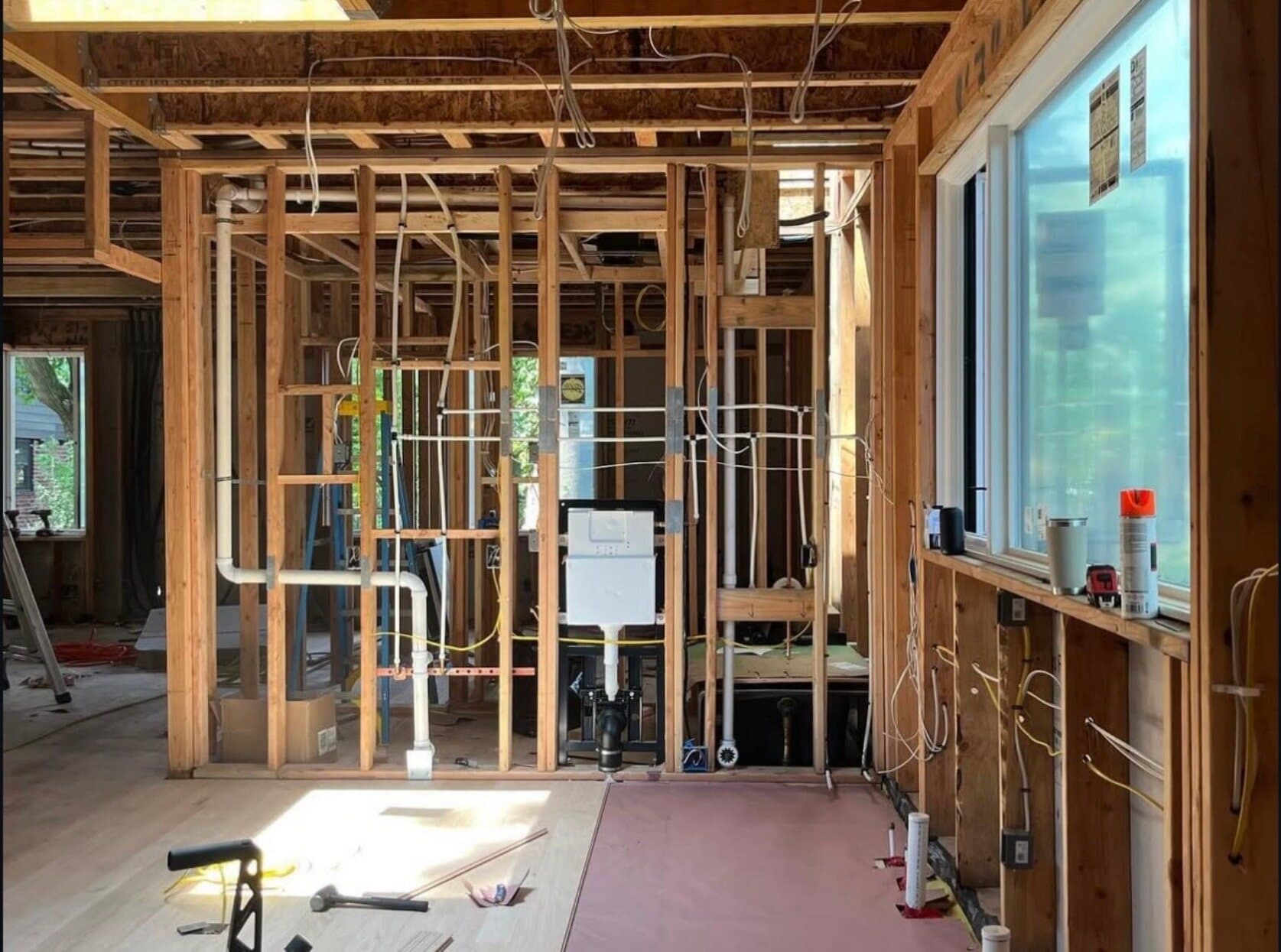 Construction photograph of interior mechanical, electrical, and plumbing rough-in work within the framed walls.