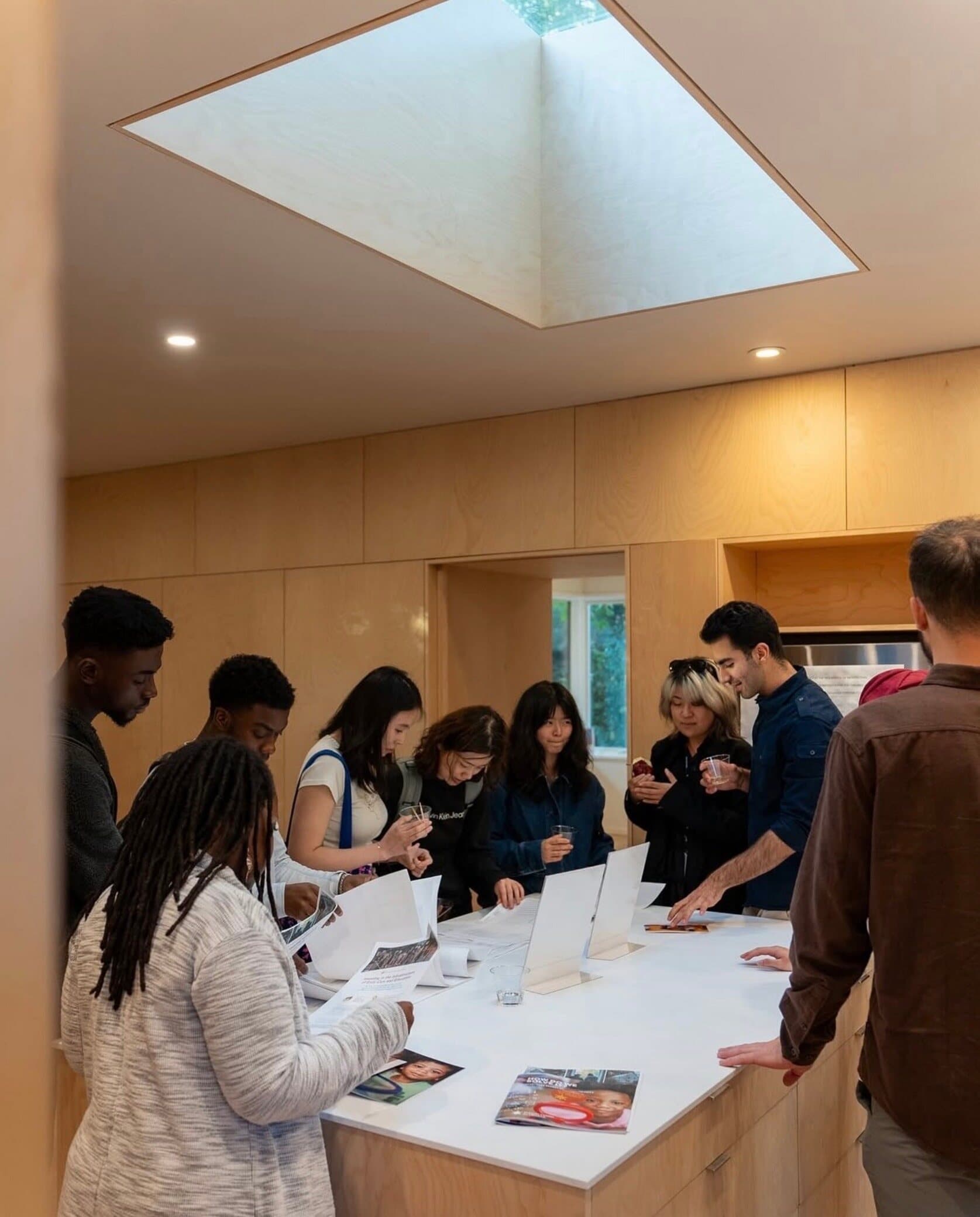 Photograph of a group gathered around a table beneath the skylight in the finished house.